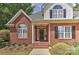 Inviting front entrance features a classic brick facade, covered porch, and meticulously maintained landscaping at 1090 Heather Glen Dr, Matthews, NC 28104