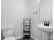 Clean, simple bathroom with a pedestal sink, toilet, and storage shelf with a stylish black faucet at 11040 E Lake Rd, Charlotte, NC 28215