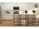 Modern kitchen with white cabinets, stainless steel appliances, an island with seating, and light wood floors at 1552 Croydon St, Indian Land, SC 29707