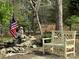 A backyard bench sits by a small waterfall with a statue and an American flag waving at 179 Tomahawk Ln, Mount Gilead, NC 27371