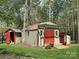 A beige outbuilding with a red roof, red doors, flower boxes, and a wooden pergola at 179 Tomahawk Ln, Mount Gilead, NC 27371