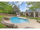 Backyard pool featuring stone accents, mature trees, and a wooden perimeter fence at 212 Horn Tassel Ct, Indian Trail, NC 28079
