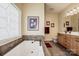 Bright bathroom featuring soaking tub, tile floors, vanity, and decorative stained glass window at 227 Donsdale Dr, Statesville, NC 28625