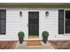 Close up of the front door with black hardware, sconces, and symmetrical potted greenery at 2413 Bergen Ct, Charlotte, NC 28210