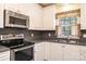 A kitchen features stainless steel appliances, gray countertops, white cabinets, and a window above sink at 2426 36Th Ne Ave, Hickory, NC 28601