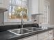 Close-up of a stainless steel kitchen sink with a window view and black countertops at 405 N Wilson St # 103, Rock Hill, SC 29730