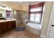 Bathroom with a glass shower, vanity with dark wood cabinets, a soaking tub under a window, and beige tile at 447 Shagbark Ct, Mount Gilead, NC 27306