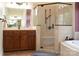 Well-lit bathroom features a glass-enclosed shower, vanity with dark wood cabinets, and a soaking tub at 447 Shagbark Ct, Mount Gilead, NC 27306
