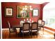 Elegant dining room with wood table, upholstered chairs, chandelier, and decorative paintings on the red walls at 447 Shagbark Ct, Mount Gilead, NC 27306