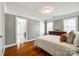 Bedroom with hardwood floors, neutral paint, open ensuite bathroom, windows, and a large dresser at 5103 Trinity Trace Ln, Monroe, NC 28110