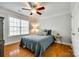 Cozy bedroom features wood floors, a ceiling fan, a window with blinds, and a comfortable bed at 5103 Trinity Trace Ln, Monroe, NC 28110