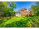 Expansive backyard view showcases a well-maintained lawn and brick home with a screened porch, blending indoor and outdoor living at 5103 Trinity Trace Ln, Monroe, NC 28110