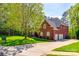 Well-maintained brick home features a lush lawn, mature trees, and an expansive driveway, creating a serene residential setting at 5103 Trinity Trace Ln, Monroe, NC 28110