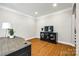 A well-lit office area with hardwood floors, a desk, and a television on an elegant credenza at 5103 Trinity Trace Ln, Monroe, NC 28110