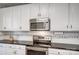 Updated kitchen features sleek black countertops, stainless steel appliances, and white cabinets at 62 Pond View Ln, Fort Mill, SC 29715
