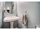 Stylish powder room with a pedestal sink, an oval mirror, and a decorative towel ring at 62 Pond View Ln, Fort Mill, SC 29715