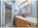 Light blue bathroom with a wooden vanity, white sink, mirror, and tiled shower at 6809 Copernicus Cir, Charlotte, NC 28226