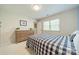 Bright bedroom with a checkered quilt bed, a wooden dresser, and ample natural light from the window at 6809 Copernicus Cir, Charlotte, NC 28226