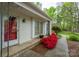 A well lit and clean entryway with a red front door and white brick walls and trim, bordered by azaleas at 6815 Old Post Rd, Charlotte, NC 28212
