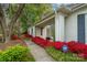 The beautiful home has a white brick exterior with a walkway bordered with vibrant azaleas leading to the front door at 6815 Old Post Rd, Charlotte, NC 28212