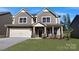 Charming two-story home boasts a stone facade, a well-manicured lawn, and attached two car garage at 7023 Butternut Oak Ter, Huntersville, NC 28078