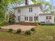 An inviting backyard with a gravel patio, steps leading up to french doors, and manicured bushes at 740 Woodlawn Ave, Mount Holly, NC 28120