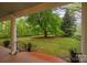 View from the porch looking onto the large green lawn, beautiful landscaping, and mature trees in the backyard at 740 Woodlawn Ave, Mount Holly, NC 28120