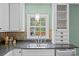 A kitchen sink beneath a window is set in a granite countertop with detailed white cabinets at 740 Woodlawn Ave, Mount Holly, NC 28120