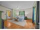 Bright main bedroom featuring hardwood floors, area rug, and windows with decorative curtains and trim at 740 Woodlawn Ave, Mount Holly, NC 28120