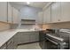 Well-organized laundry room features gray cabinets, open wood shelves, patterned wallpaper, and modern washer and dryer at 9611 Pensive Ln, Waxhaw, NC 28173