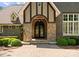 Elegant entrance with arched doorway, stone accents, and lush landscaping at 10915 Hermit Thrush Ln, Charlotte, NC 28278