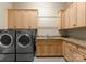 Functional laundry room featuring modern washer and dryer, sink, and storage cabinets at 10915 Hermit Thrush Ln, Charlotte, NC 28278