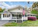 Charming single-story home with a covered front porch, American flag, and well-maintained landscaping at 1106 University Dr, Lancaster, SC 29720