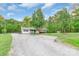 Charming single-story home with a welcoming front porch, lush landscaping, and a gravel driveway at 1106 University Dr, Lancaster, SC 29720