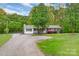 Inviting single-story home with a welcoming front porch, lush landscaping, and a gravel driveway at 1106 University Dr, Lancaster, SC 29720