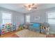 Bedroom with a gray crib, ceiling fan, hardwood floors, and natural light from surrounding windows at 1116 Montgomery Ave, Albemarle, NC 28001