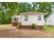 Shot of the home's exterior with white siding, a red brick base, trimmed bushes, and manicured lawn at 1116 Montgomery Ave, Albemarle, NC 28001