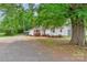 Lovely single-story home with a well-maintained front yard and a gravel driveway, shaded by mature trees at 1116 Montgomery Ave, Albemarle, NC 28001