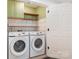 Bright laundry room with white subway tile, wooden shelving and modern Samsung washer and dryer at 1124 Culver Spring Way, Charlotte, NC 28215