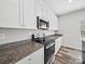 Well-lit kitchen with granite countertops, stainless steel appliances and sleek white cabinetry at 113 Fosters Glen Pl, Mooresville, NC 28115