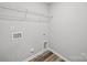 Bright laundry room with wood-look floors, utility sink, and wire shelving at 113 Fosters Glen Pl, Mooresville, NC 28115