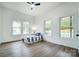 Bright bedroom with wood-look floors, white walls, ceiling fan, and three windows providing natural light at 113 Woodside Ave, Gastonia, NC 28054