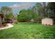Lush backyard with patio, storage shed and mature trees, providing a serene outdoor space at 115 Stumpy Creek Rd, Mooresville, NC 28117