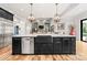 Modern kitchen island with sink, dishwasher, black cabinets, quartz countertops, and views into living space at 129 Hunts Landing Dr, Mooresville, NC 28117