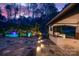 An idyllic outdoor kitchen overlooks a luxurious pool and water feature under a colorful twilight sky at 129 Hunts Landing Dr, Mooresville, NC 28117