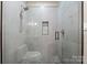 A modern shower with gray tiling, decorative pebble floor, glass doors, and a handheld shower fixture at 129 Hunts Landing Dr, Mooresville, NC 28117