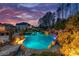 A stunning backyard oasis with a gunite pool, rock waterfall, and elegant landscaping at twilight at 129 Hunts Landing Dr, Mooresville, NC 28117