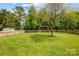 Large backyard with lush green lawn, mature trees, a swing set, and a storage shed at 13715 Sunrise View Dr, Charlotte, NC 28278