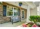 Inviting front porch with stone accents, bench seating, decorative plants, and a hanging flower basket at 13715 Sunrise View Dr, Charlotte, NC 28278