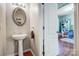 Stylish powder room with a pedestal sink, decorative mirror, and access to the adjacent playroom at 13715 Sunrise View Dr, Charlotte, NC 28278